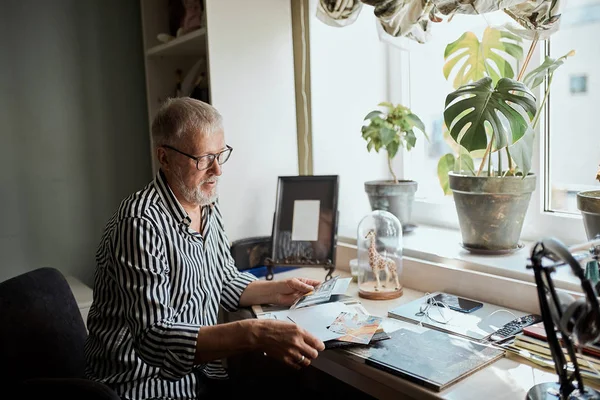 Hombre maduro mirando sus viejas fotos de boda mientras está sentado en casa — Foto de Stock