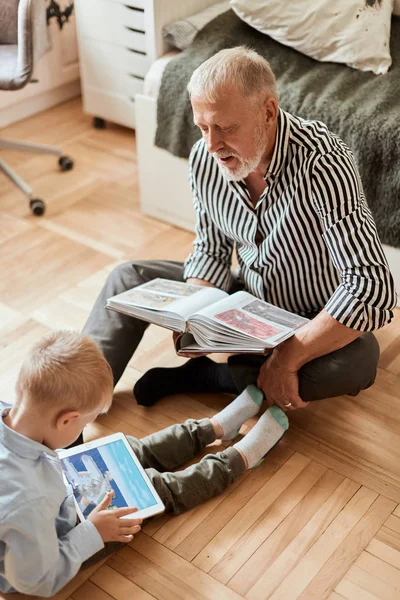 Morfar ser fotoalbum med sitt bröllop, liten pojke med hjälp av elektronisk tablett — Stockfoto