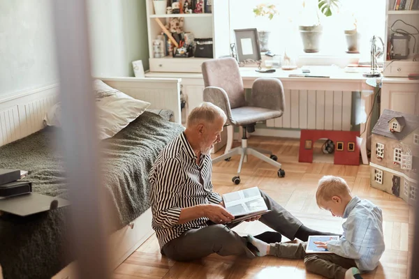 Nonno guarda album fotografico con il suo matrimonio, bambino utilizzando tablet elettronico — Foto Stock