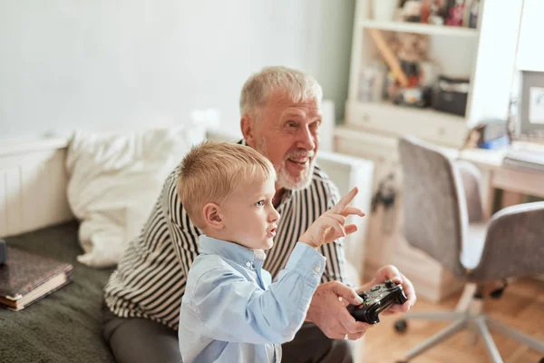 Παππούς και εγγονός παίζουν βιντεοπαιχνίδια στον υπολογιστή με χειριστήριο — Φωτογραφία Αρχείου