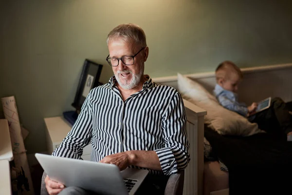 Nonno e nipote usando gadget e sorridendo mentre passano del tempo insieme seduti sul divano — Foto Stock