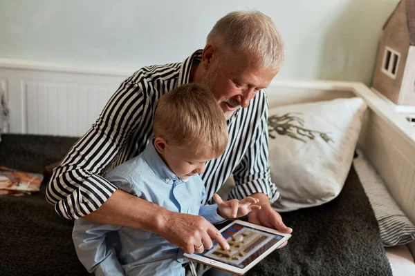 Dědeček a vnuk pomocí digitálního tabletu při sezení na gauči — Stock fotografie