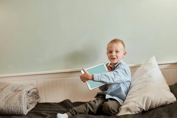 Niño con tableta digital sentado en el sofá, en la sala de estar — Foto de Stock