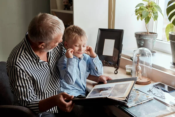 Nonno e nipote sul divano di casa. Nonno e bambini guardando vecchie foto — Foto Stock