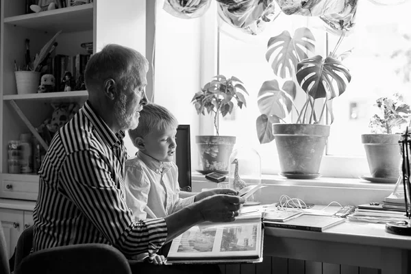 Abuelo y nieto en el sofá en casa. Abuelo y niños viendo fotos viejas —  Fotos de Stock