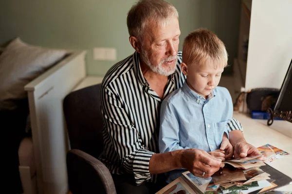 Abuelo y nieto en el sofá en casa. Abuelo y niños viendo fotos viejas —  Fotos de Stock