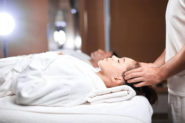 Mooie jonge vrouw ontvangt massage op hoofd en schouders zone in spa centrum — Stockfoto