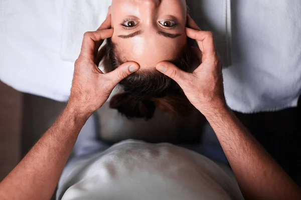 Mujer disfrutando de masaje facial anti envejecimiento. Foto al revés de la mujer relajante — Foto de Stock