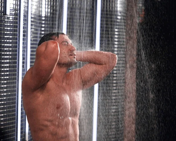 Hombre guapo tomando una ducha, refrescándose después de un día de trabajo caliente . — Foto de Stock