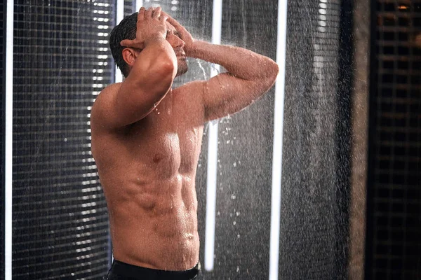 Hombre guapo tomando una ducha, refrescándose después de un día de trabajo caliente . — Foto de Stock