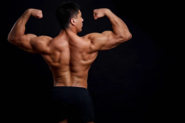 Bodybuilder med upphöjda armar poserar för kameran — Stockfoto