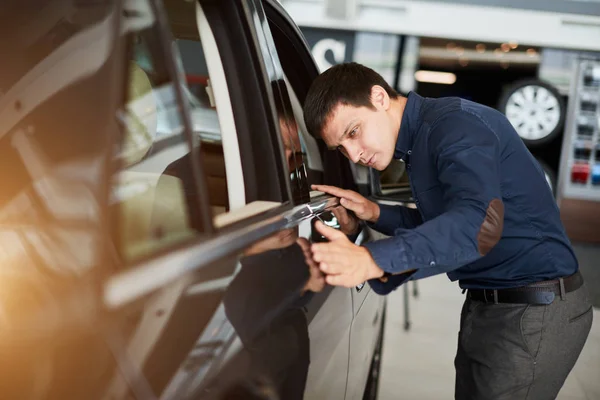 Auto biznes, sprzedaż samochodów i koncepcja ludzi - szczęśliwy uśmiechnięty biznesmen lub dealer w garniturze na tle auto show — Zdjęcie stockowe