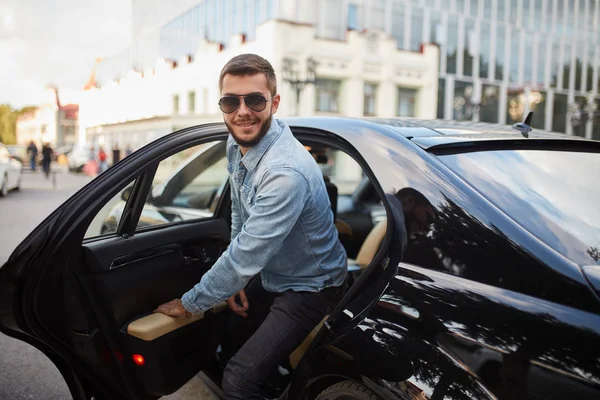 Positiv aussehender Mann mit Brille verlässt das schwarze Auto — Stockfoto