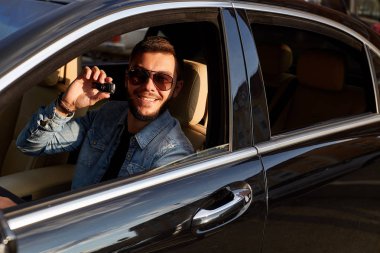 Yeni bir araba sunan pozitif genç adam