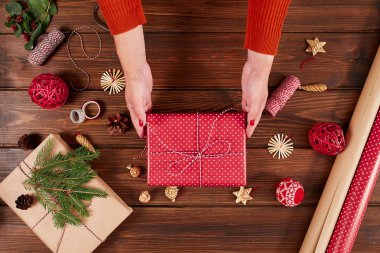 Kadın hediye paketi ve ahşap masa üzerindeki dekorasyon malzemeleri, yakın, üst görünüm.