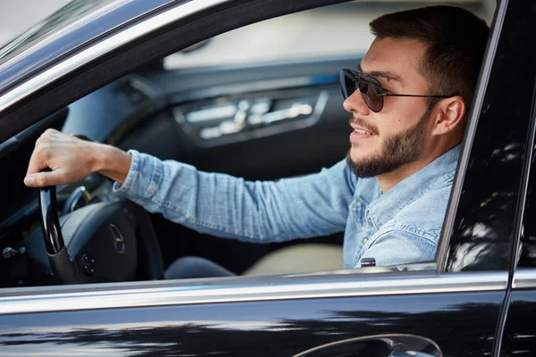 smiling bearded man renting a stylish car