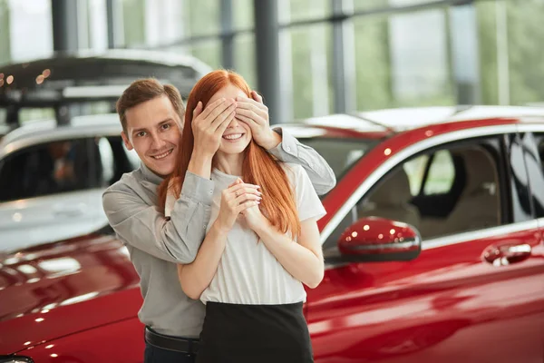 Uomo che fa una sorpresa per sua moglie, che le compra una macchina nuova in concessionaria. — Foto Stock