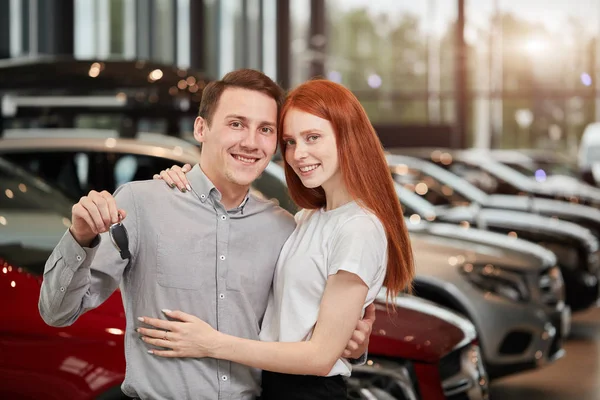 Beautiful couple is holding key of their new car, looking at camera and smiling — Stock Photo, Image