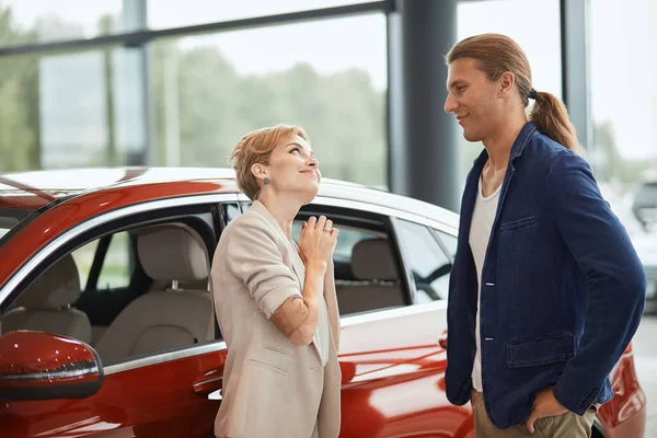 행복 한 젊은 아내가 대리점에서 새 차를 사 달라고 부탁하는 모습. — 스톡 사진