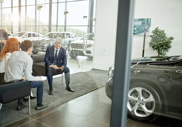 Feliz hermosa pareja está comprando un coche nuevo en la concesionaria. Consejo familiar — Foto de Stock