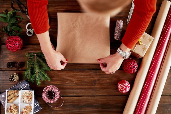 女人的手把圣诞礼物包在深色的木制背景上. — 图库照片