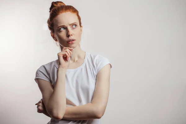 Rothaarige Frau blickt mit nachdenklichem Gesichtsausdruck isoliert auf weißem Hintergrund auf. — Stockfoto