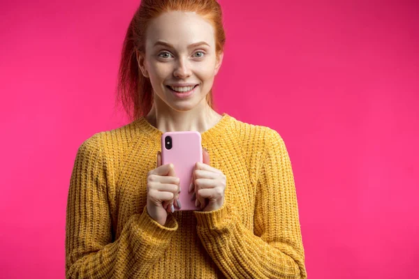 Porträt von niedlichen Ingwermädchen mit Smartphone isoliert auf rosa b — Stockfoto