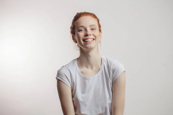 Menina ruiva com coque de cabelo e sardas isoladas sobre fundo cinza — Fotografia de Stock