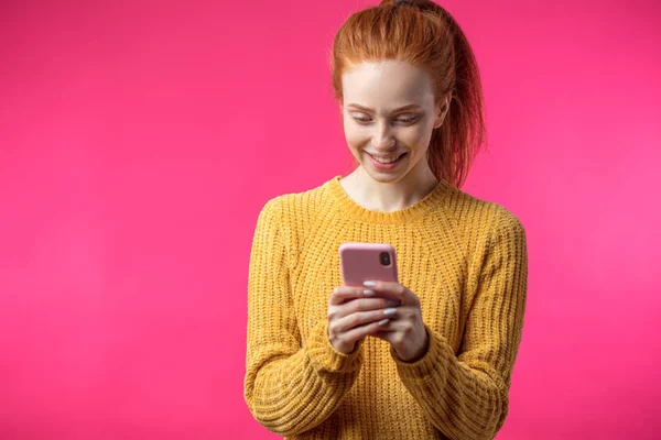 Retrato de linda chica de jengibre usando teléfono inteligente aislado sobre fondo rosa — Foto de Stock