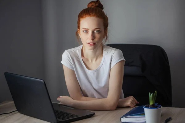 Портрет рыжеволосой молодой женщины с цифровой табличкой, сидящей за столом — стоковое фото