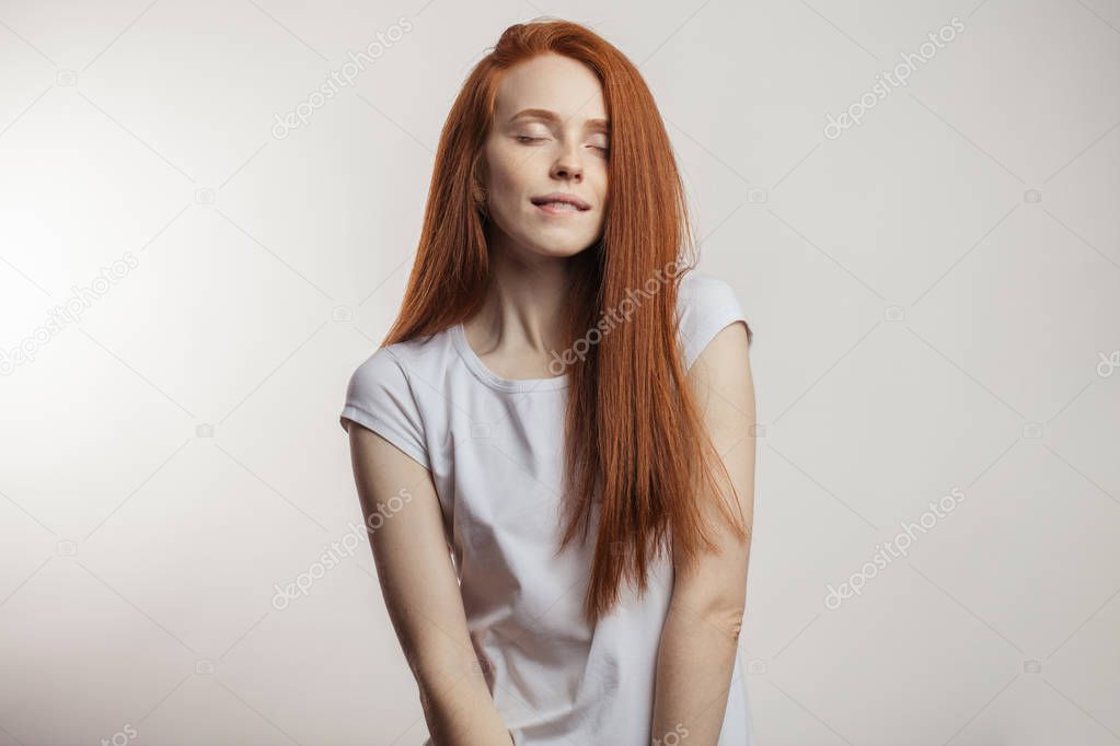 Portrait of a cheerful redhaired emotional woman in positive mood at studio.