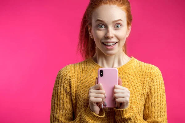 Porträt von niedlichen Ingwermädchen mit Smartphone isoliert auf rosa b — Stockfoto