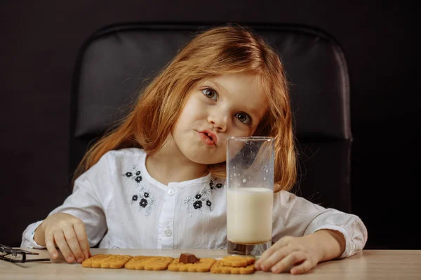 Menina bonita feliz fazendo um lanche com leite e biscoitos — Fotografia de Stock