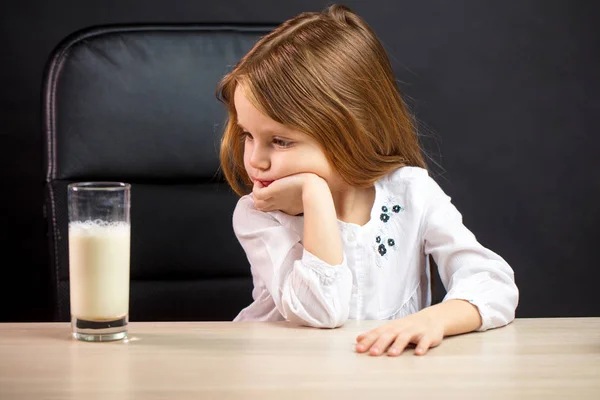 Menina sombria em óculos se recusando a beber leite, sobre preto — Fotografia de Stock
