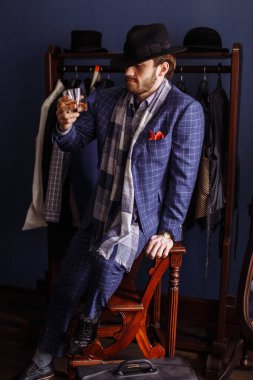 Moda bir takim elbisesi ve içecek ile atelier, poz zarif erkekte