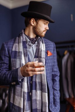 Moda bir takim elbisesi ve içecek ile atelier, poz zarif erkekte