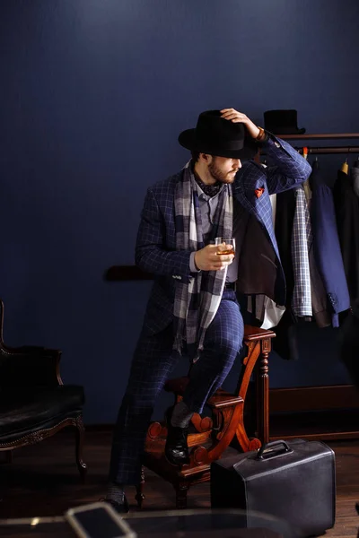 Elegantní muž v módní oblek a klobouk pózuje v ateliéru s nápojem — Stock fotografie