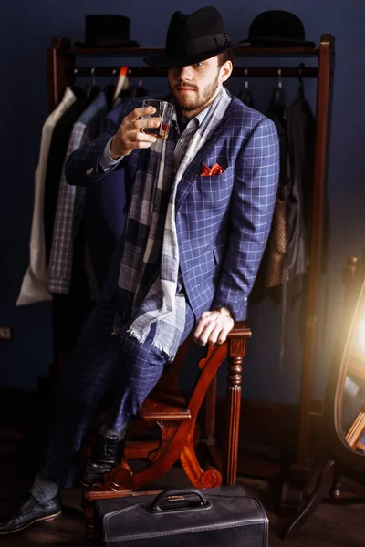 Elegantní muž v módní oblek a klobouk pózuje v ateliéru s nápojem — Stock fotografie