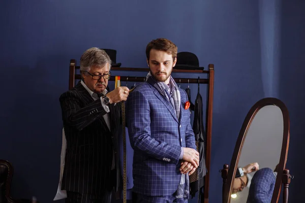 Mature professional Tailor taking measure leg measuring of client customer — Stock Photo, Image