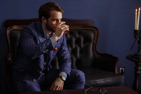 Joven guapo en un traje clásico bebiendo vino tinto en el restaurante —  Fotos de Stock