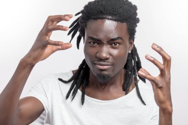 Saçları rastalı genç ve duygusal Afrikalı bir adam beyazın üzerinde tek başına duruyor. Kameraya bak.