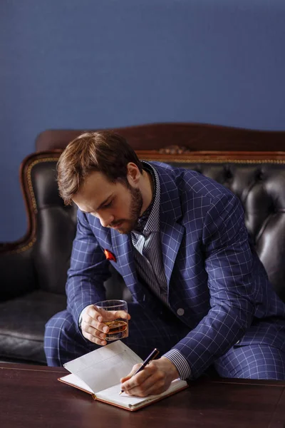 レストランで赤ワインを飲む古典的なスーツでハンサムな若い男 — ストック写真