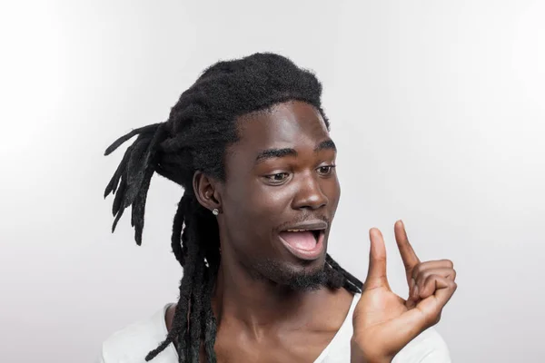 Dark skinned man showing small thing while smiling and standing near white background — Stock Photo, Image