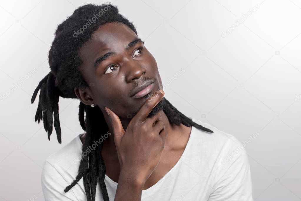 Thinking or dreaming african man with dreadlocks on white background