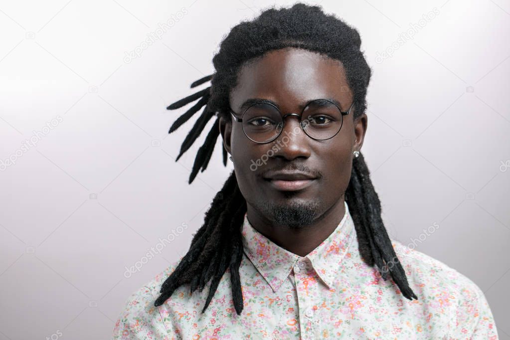 young handsome African man wearing flowers shirt against yellow background