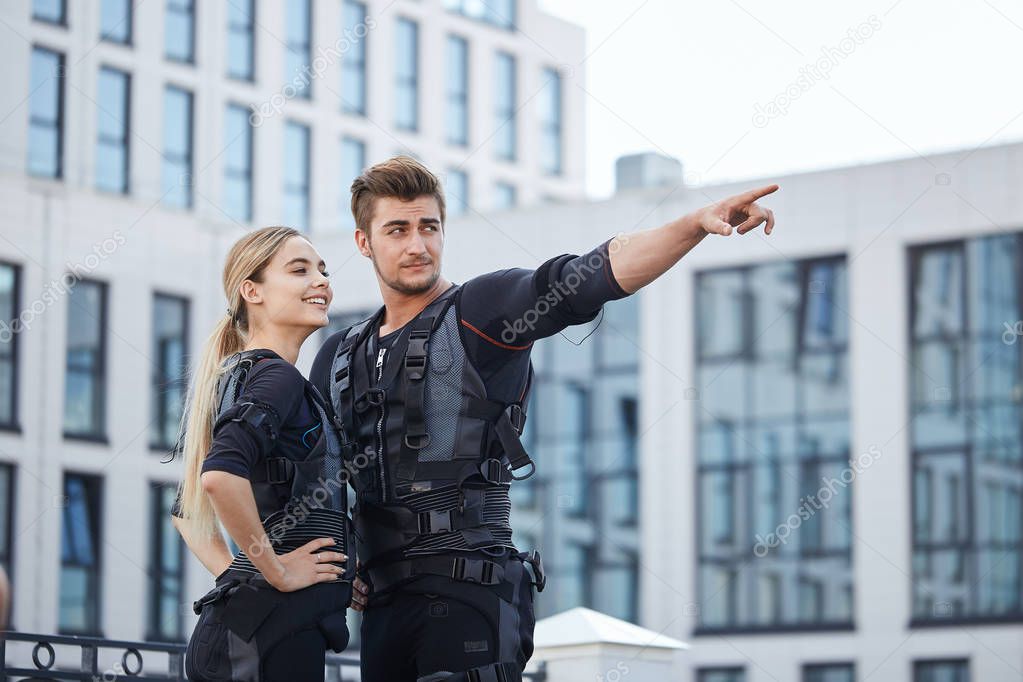 sporty strong man showing a modern building to a good looking girlfriend