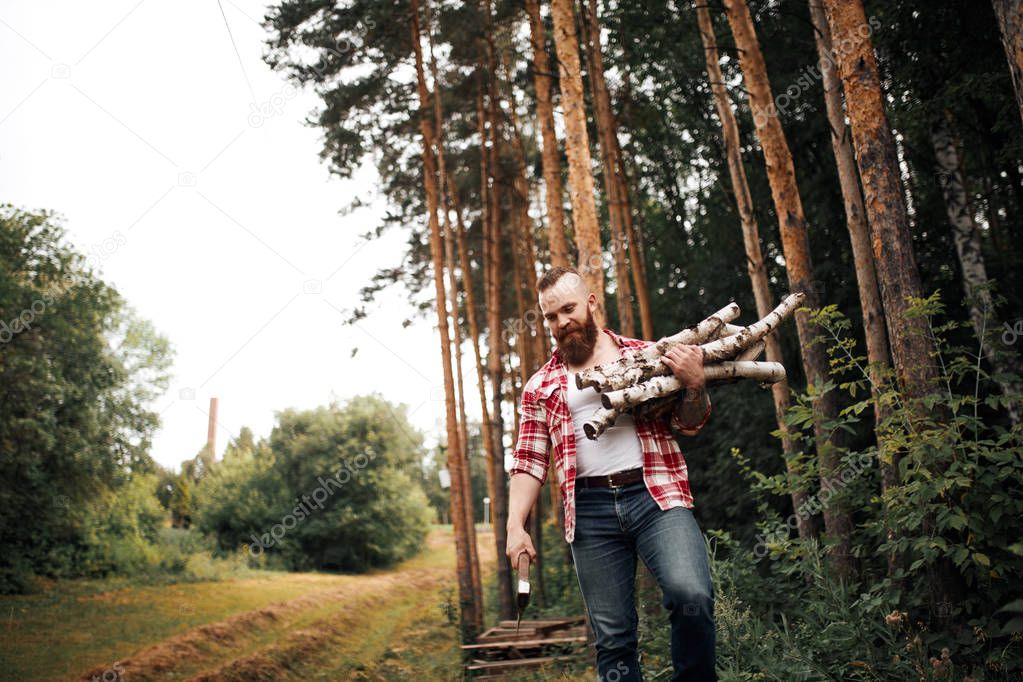 Bearded Man with firewoods and with axe on shoulder