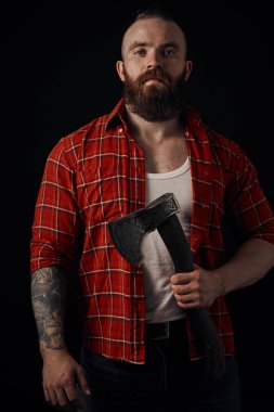 Göğsünde baltası olan sakallı bir erkek stüdyoda poz veriyor.