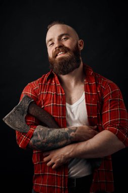 smiling bearded man holding axe looking at camera on black background clipart