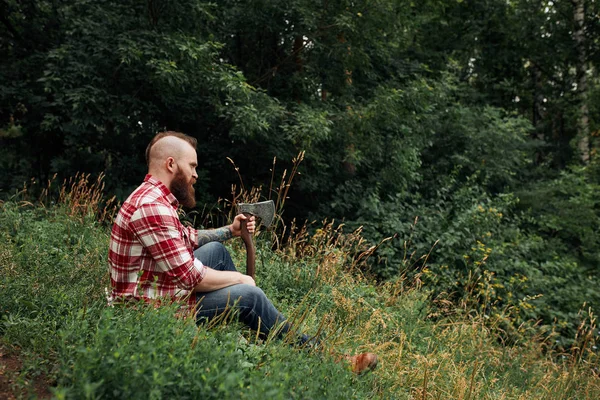 Dřevorubec sedí v lese a odpočívá po tvrdé práci — Stock fotografie